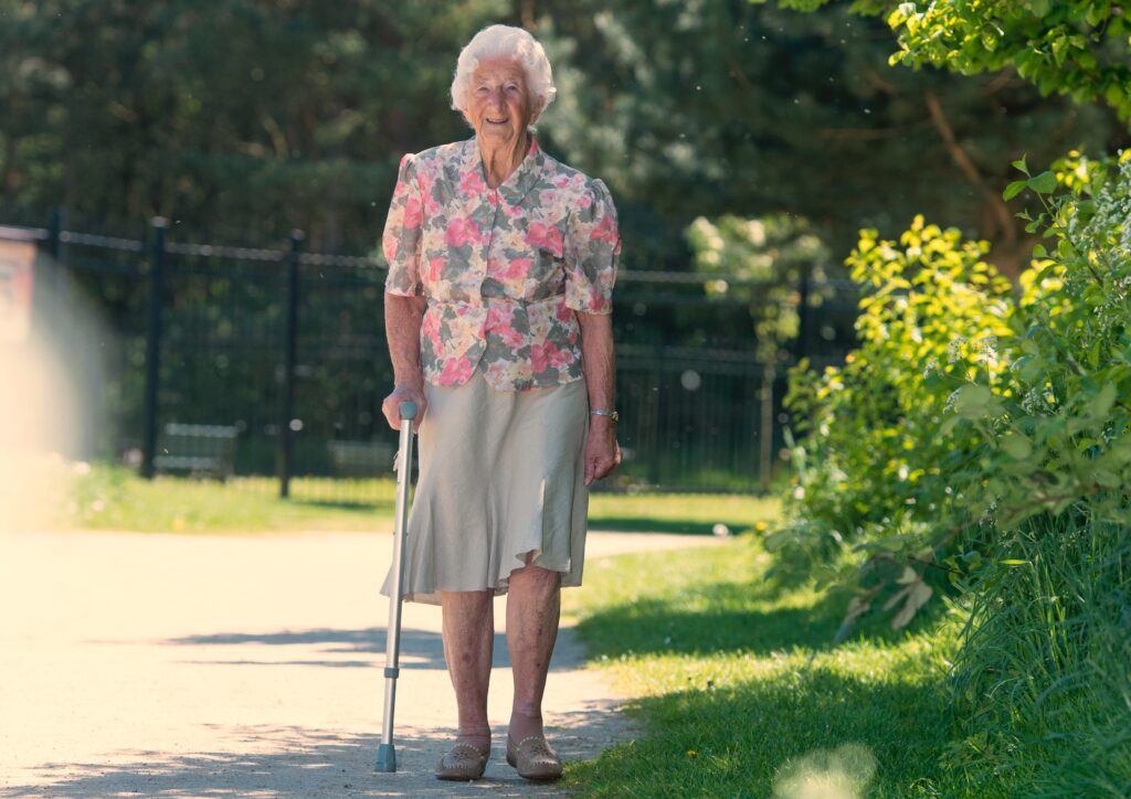 Elderly lady walking in a park with a walking stick